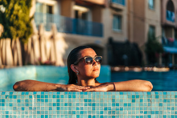 Pretty brunette girl relaxing at the swimming pool