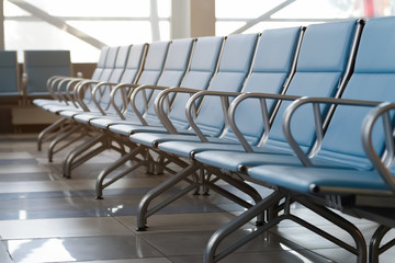 Empty airport terminal waiting area with chairs.