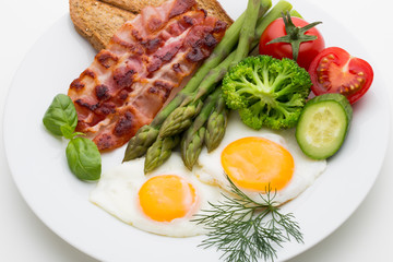 Fried eggs with bacon on the wooden table.
