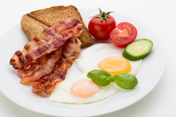 Fried eggs with bacon on the wooden table.