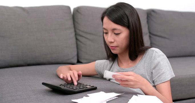 Woman counting the spending of the daily life at home with lots of receipt and calculator