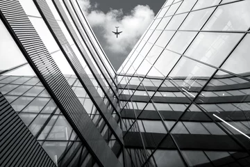 Photo sur Plexiglas construction de la ville Avion volant au-dessus d& 39 un bâtiment d& 39 architecture moderne, image à contraste élevé en noir et blanc à faible angle