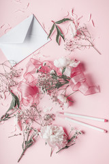 Pastel pink flowers and envelope, top view, flat lay