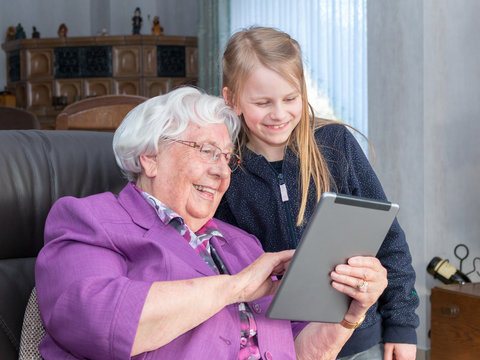 Gro&szlig;mutter, die ihrem Enkelkind etwas lustiges auf ihrem Tablet zeigt