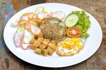 Fried rice with vegetables, rice chips, cheese tofu and fried egg on the table, close up
