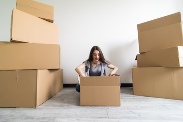 Woman packing and unpacking belongings in a carton box when moving home. Relocation.