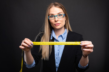 Business lady wearing blue glasses holding measuring tape.