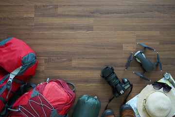 Overhead view of Traveler's accessories, trip vacation, tourism mockup, backpack, camera, drone, shoes with map on wooden table background,Top view on wood floor