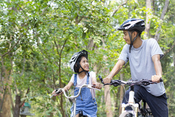 Naklejka na ściany i meble Happy father and daughter cycling in the park, togetherness relaxation concept