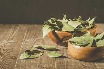bay leaf on a wooden surface in a two wooden bowl/spices of bay leaf in rural style on a wooden table. Copy space