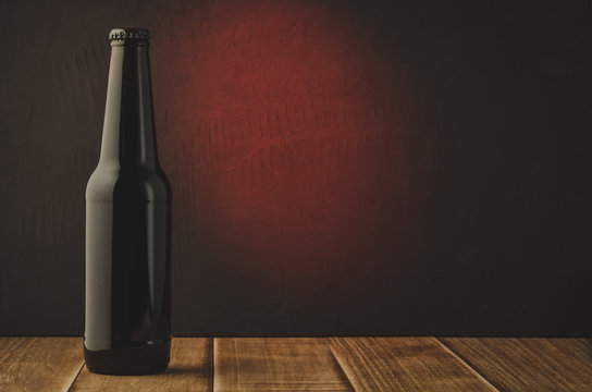 black beer bottle with red light background/black beer bottle with red light background. Selective focus and copyspace