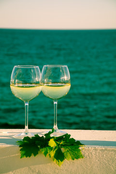 Two glasses with cold white wine served outside on terrace with green grape vine, luxury resort with sea view, romantic vacation