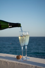 Two glasses with champagne or cava served outside on terrace, luxury resort with sea view, romantic vacation