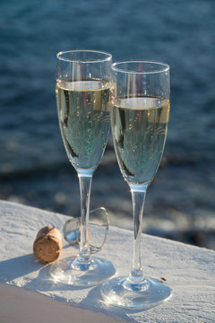 Two glasses with champagne or cava served outside on terrace, luxury resort with sea view, romantic vacation