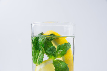 Fresh Cool Infused Detox Water with Ripe Organic Sliced Lemons Mint in Tall Glass. White Background. Healthy Drink Detox Summer Refreshment. Copy Space