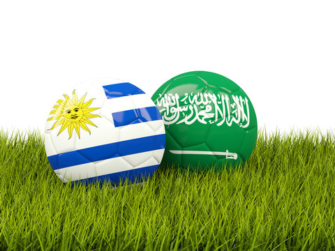 Uruguay vs Saudi Arabia. Soccer concept. Footballs with flags on green grass