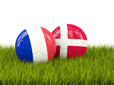 France vs Denmark. Soccer concept. Footballs with flags on green grass