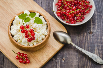 breakfast: cottage cheese with red berries and mint in a wooden bowl/breakfast: cottage cheese with red berries and mint in a wooden bowl. Top view