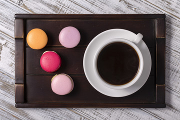 Cup of coffee and macaron cakes on tray on white wooden table. Lifestyle concept.
