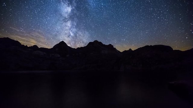 Night timelapse of the Milky Way moving over the Ibon de Estanes lake and the Pyrenees mountains in Spain
