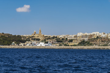 Gozo Island, Malta Gozo port landscape. Gozo Channel Line Ferry at port with background view of city buildings and Ghajnsielem Parish Church.