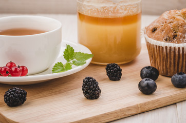 breakfast: tea with mint, cake, honey and fresh berries/healthy breakfast: tea with mint, cake, honey and fresh berries on a wooden surface. Selective focus