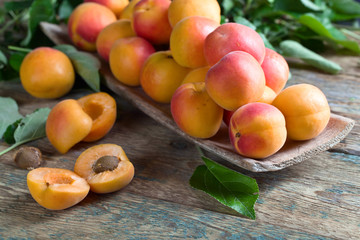 Apricots with leaves on old wooden table .