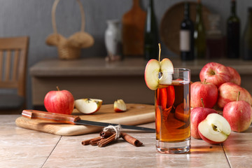Glass of apple juice and ripe pink apples on a kitchen table