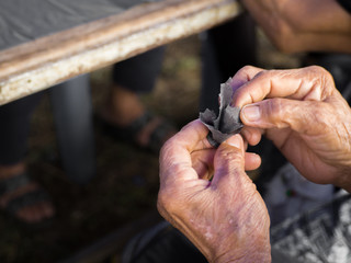 Fototapeta na wymiar Hands of an elderly woman is preparing artificial flowers. Made of coin and fabric black