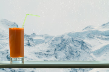A glass of carrot juice with a straw in the cafe on the background glacier Jungfrau in Switzerland 