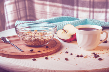 Breakfast. A bowl with muesli, a cup of coffee, the cut apple on a wooden table