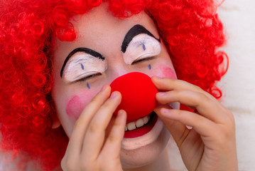 Funny kid clown with red nose playing