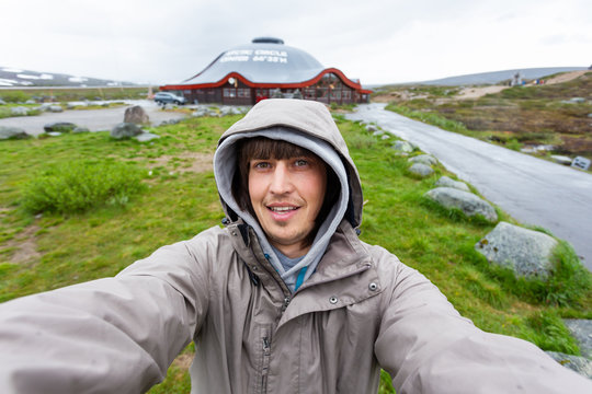 Tourist man making selfie Arctic circle center. Landmark on Lofoten islands. Norway.