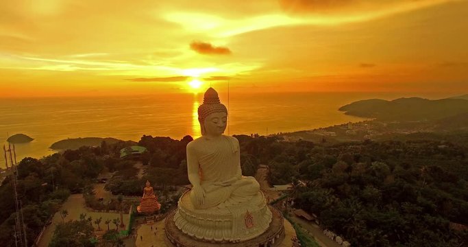 aerial view the white big Buddha statue on the high mountain in sunset time. Phuket big Buddha on hilltop can see around Phuket island behind Phuket big Buddha is Karon gulf in front is Chalong gulf.