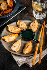 Fried asian dumplings Gyoza  on dark plate, served with chopsticks and soy sauce, dark background, copy space