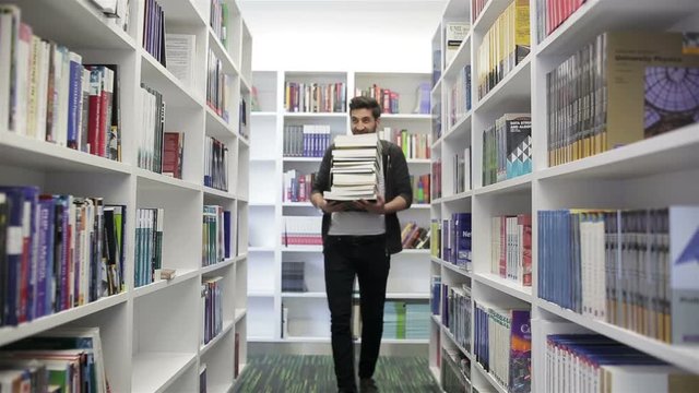 Student holding lot of books in school library. Hard worke  concept.