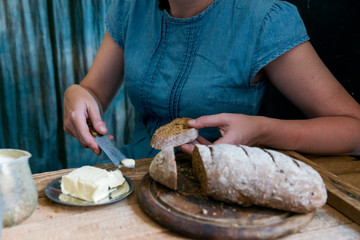 Woman puts butter on rye bread breakfast concept