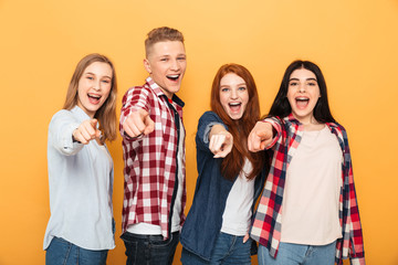 Group of happy school friends pointing fingers at camera