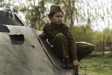 Boy in the military uniform on the tank of time of Second World War. Kids in uniform. Soldier boy....