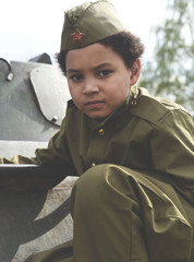 Boy in the military uniform on the tank of time of Second World War. Kids in uniform. Soldier boy....