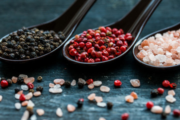 Close up pink himalayan salt and peppers in spoons