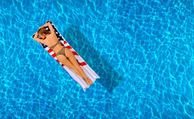 Woman in bikini on the inflatable mattress in the swimming pool.