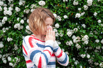 Spring allergy.  Woman blowing near spring tree in bloom.
