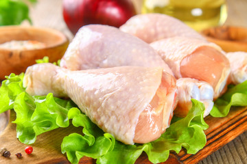 Raw chicken legs on a cutting board on an old wooden table.