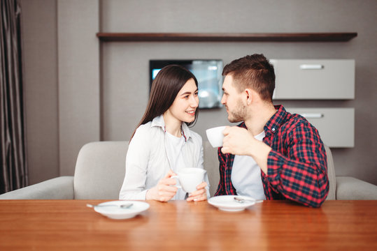 Happy love couple drinks coffee at wooden table