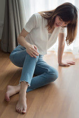 injured woman with broken knee or leg pain; portrait of asian woman falling down, breaking her knee joint, knee bone due to accident, body injury or home accident concept; 30s adult asian woman model