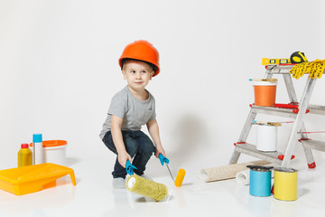 Little boy in orange protective helmet with instruments for renovation apartment isolated on white...