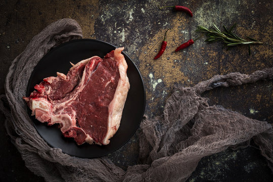 Raw beef steak. Rosemary, chilli peppers.