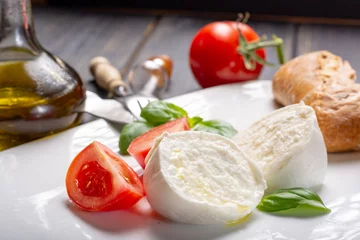 Fototapete Traditional italian food - white ball mozzarella buffalo Italian soft cheese with cheese knife, tomato, basil, olive oil © barmalini