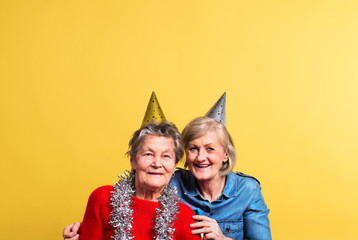 Portrait of a senior women in studio on a yellow background. Party concept.